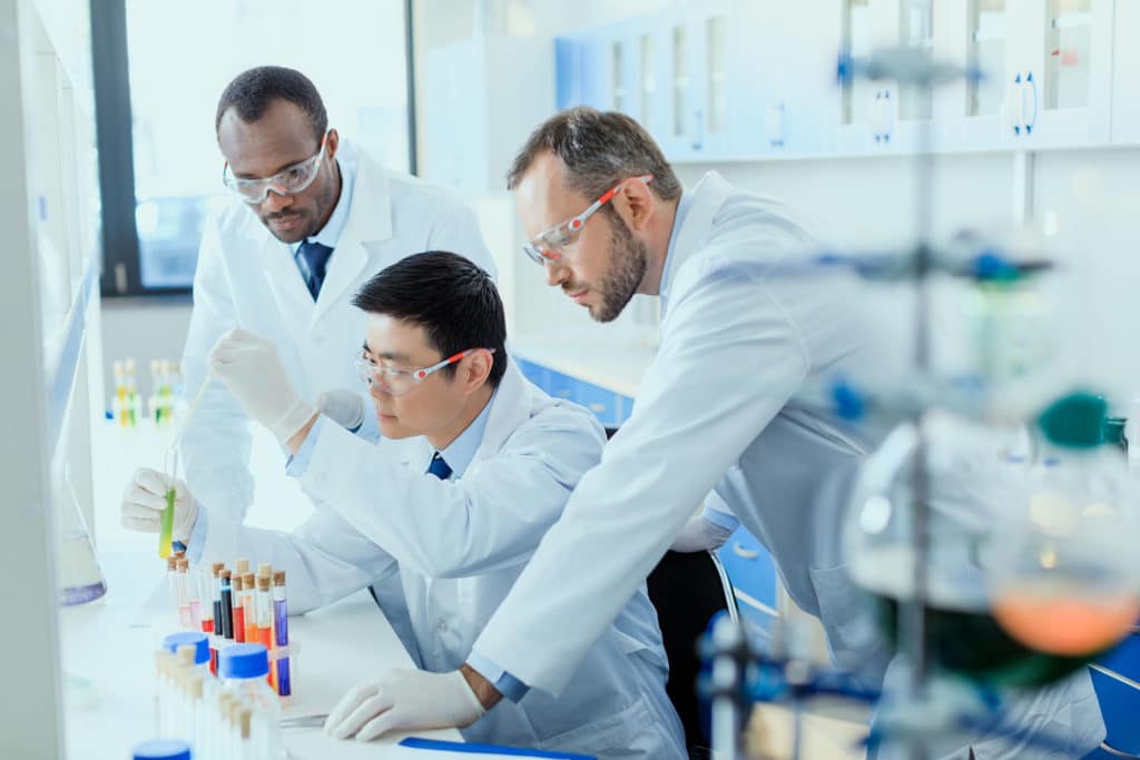 Professional scientists in white coats working together in chemical laboratory