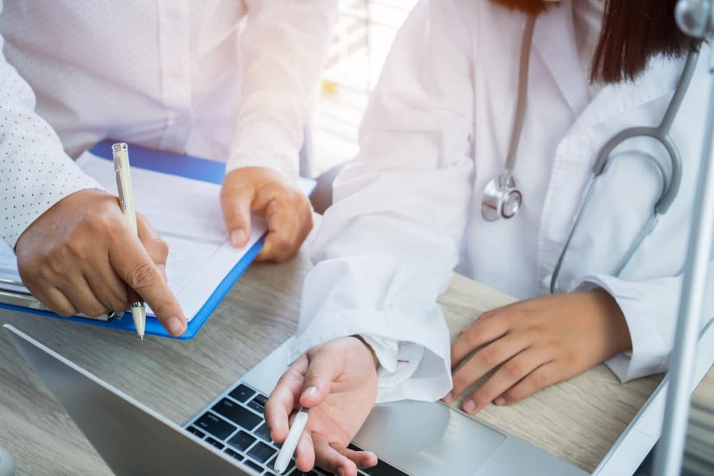 Doctors review patient info on laptop.