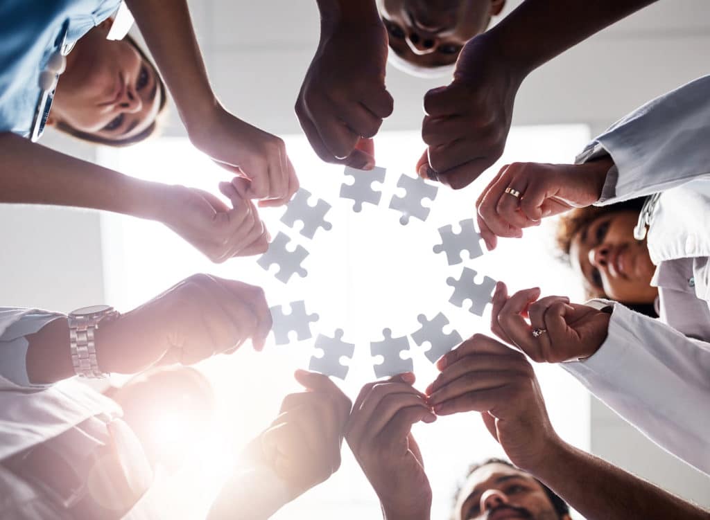 Group of doctors forming a circle with puzzle pieces.